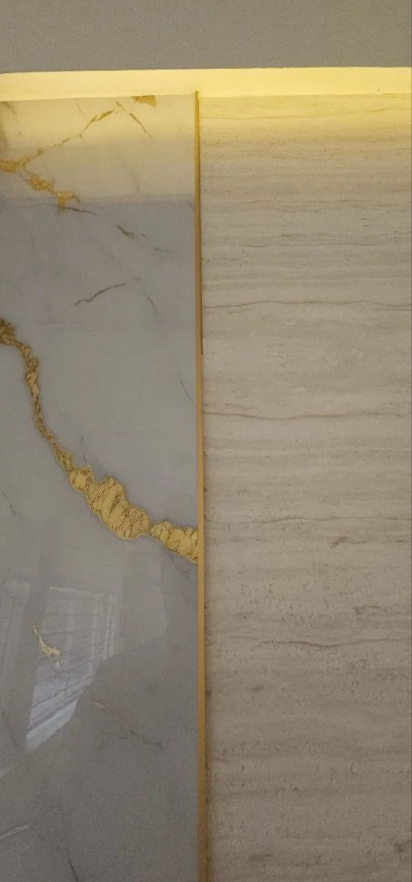 Detalle de muro de mármol blanco con vetas doradas y perfil de latón iluminado en Holy Chic, Providencia, Guadalajara