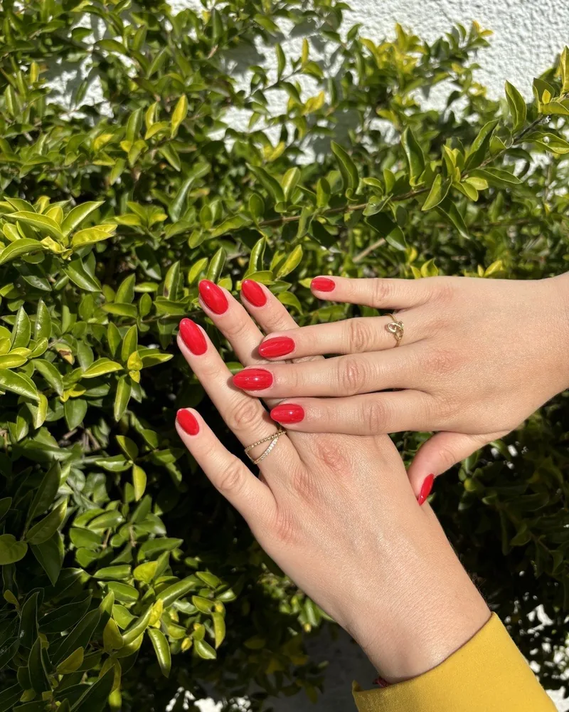 Uñas gelish rojo con anillos dorados a luz natural, salón de uñas en Providencia